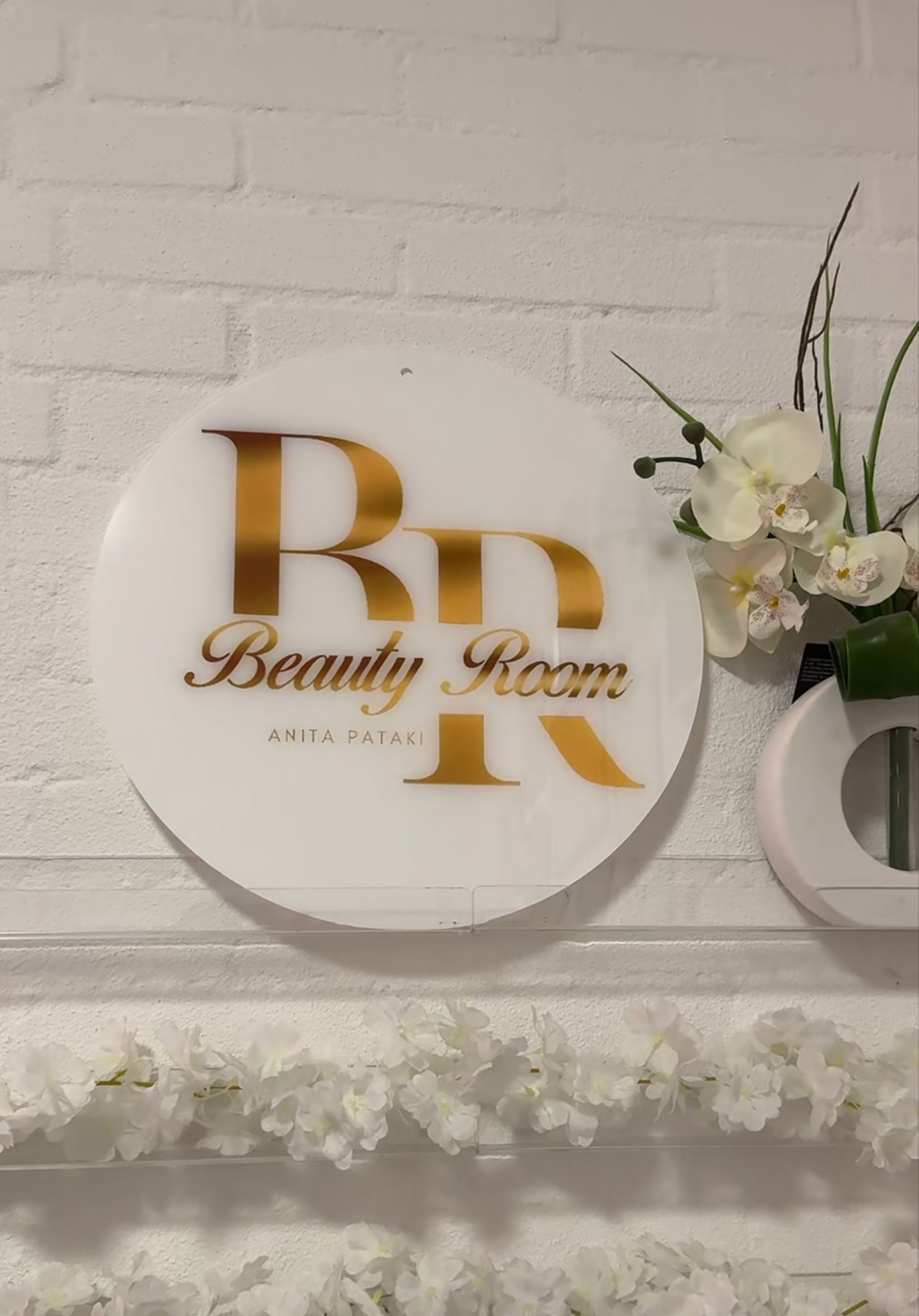 Het gouden Beauty Room-logo aan de muur van de studio
